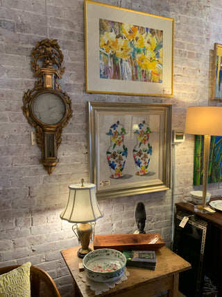Room interior with framed artwork, a clock, and decorative items on a stone floor.