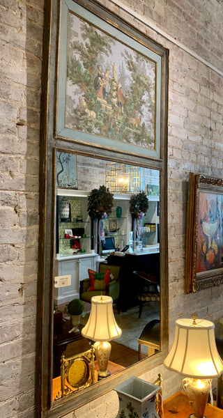 Decorative mirror with framed artwork on a brick wall