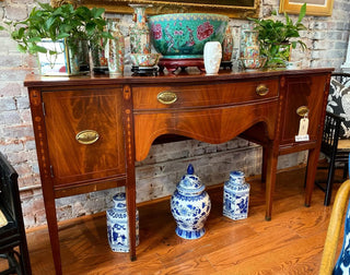 Wooden sideboard with decorative items against a brick wall.