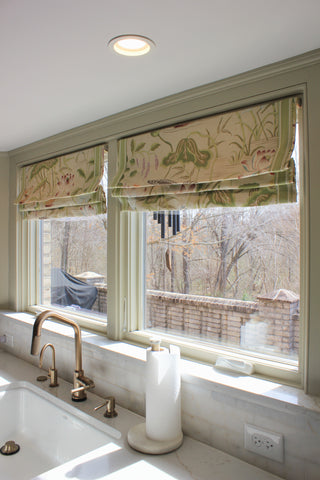 Kitchen window with floral罗马帘, marble countertop, and sink.