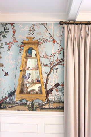Decorative wall with floral wallpaper, wooden shelf, and beige curtain.